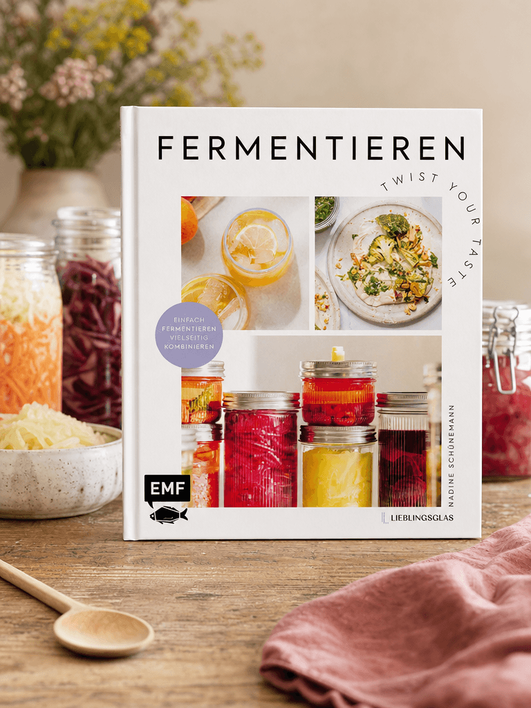 Buch „Fermentieren - Twist your Taste!“ liegt auf einem Holztisch im warmen Licht, Cover voll sichtbar
